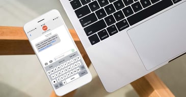 sms payment reminder message on a phone with laptop