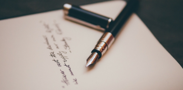 An uncapped fountain pen sitting on top of a handwritten letter